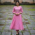 Woman wearing a pink traditional outfit standing on a stone path.
