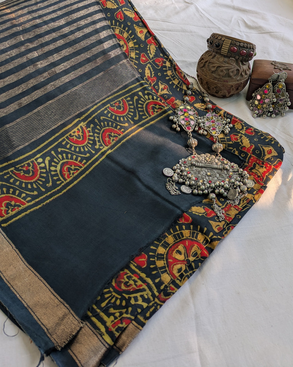 Decorative black saree with colorful patterns and jewelry on a white background
