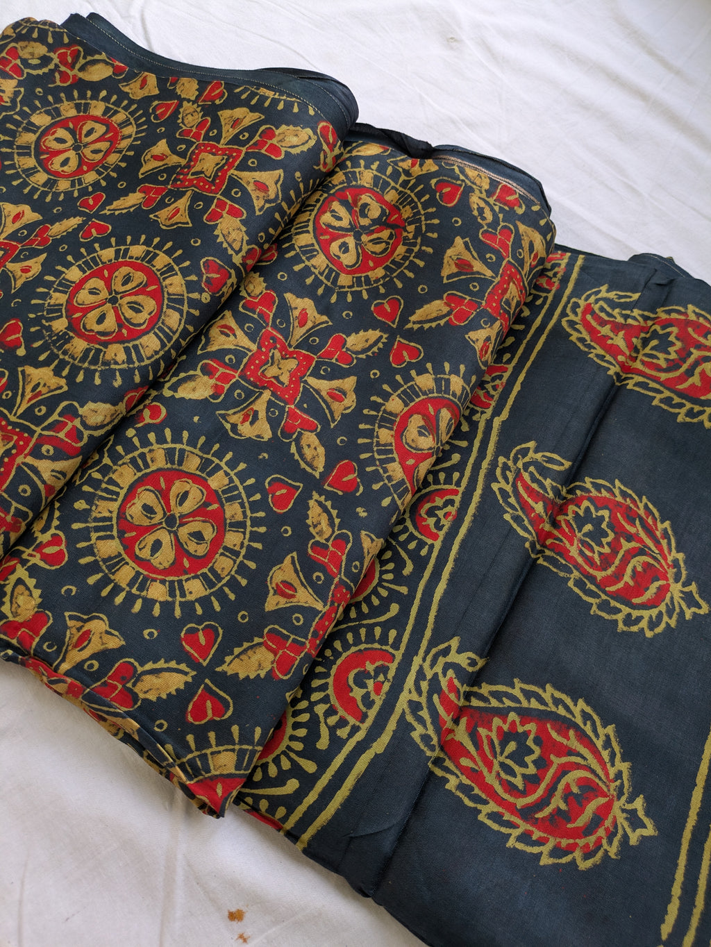 Dark fabric with red and gold intricate patterns on a white background