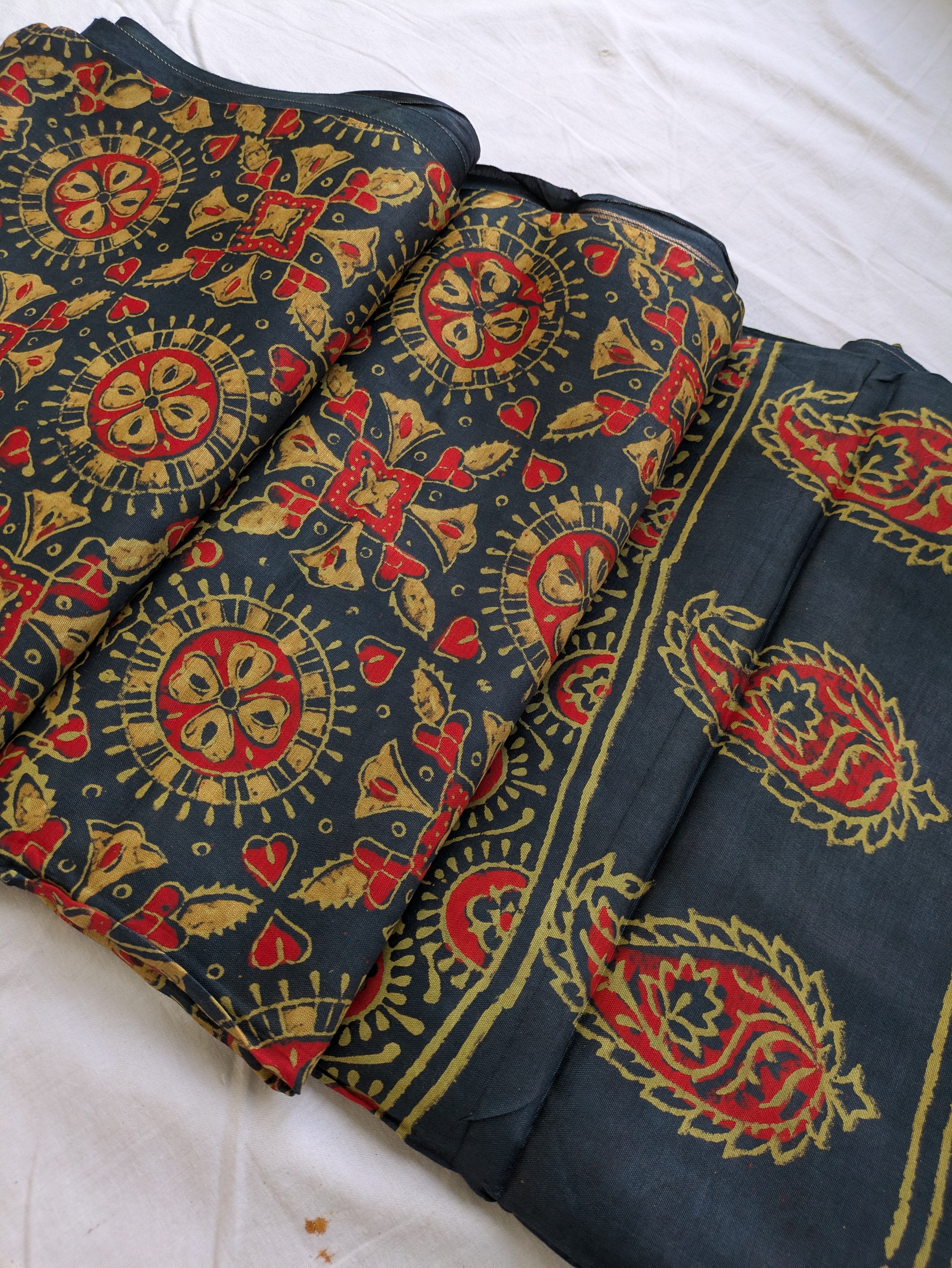 Dark fabric with red and gold intricate patterns on a white background