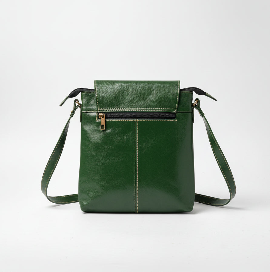 A green leather shoulder bag with a front zip pocket and a long strap, photographed on a light gray background.