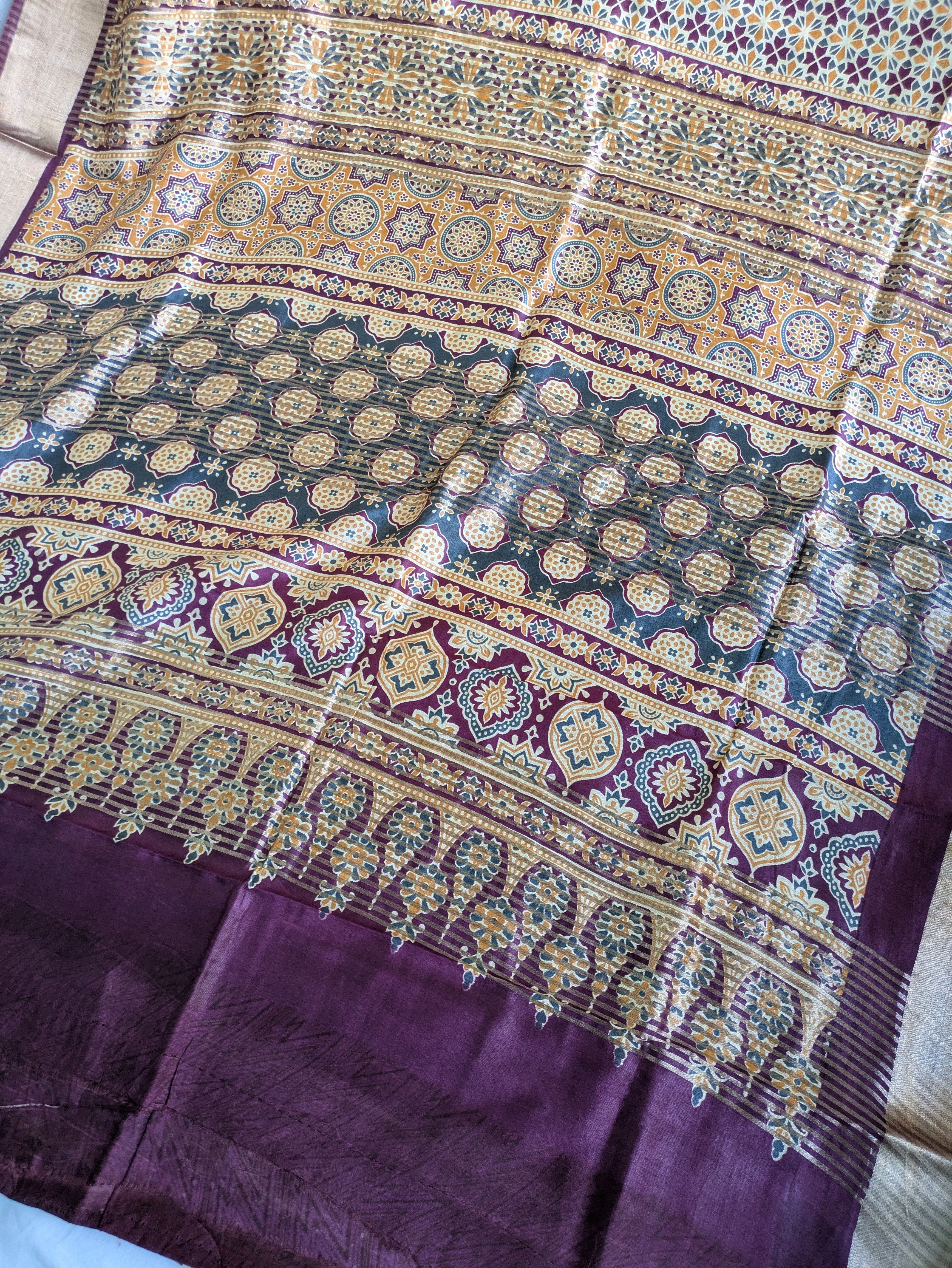 Decorative fabric with intricate patterns in purple, gold, and blue.