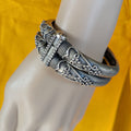Silver bracelet on a mannequin arm with a yellow background