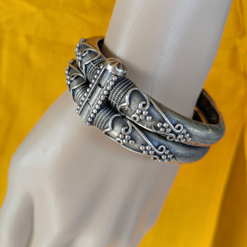 Silver bracelet on a mannequin arm with a yellow background
