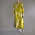 Yellow dress with white floral pattern on a mannequin against a gray background