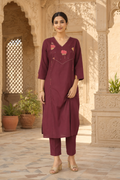 Woman wearing a maroon outfit with floral patterns in an architectural setting