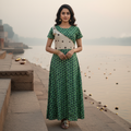 Woman in a green and white patterned dress standing by a waterfront with misty background