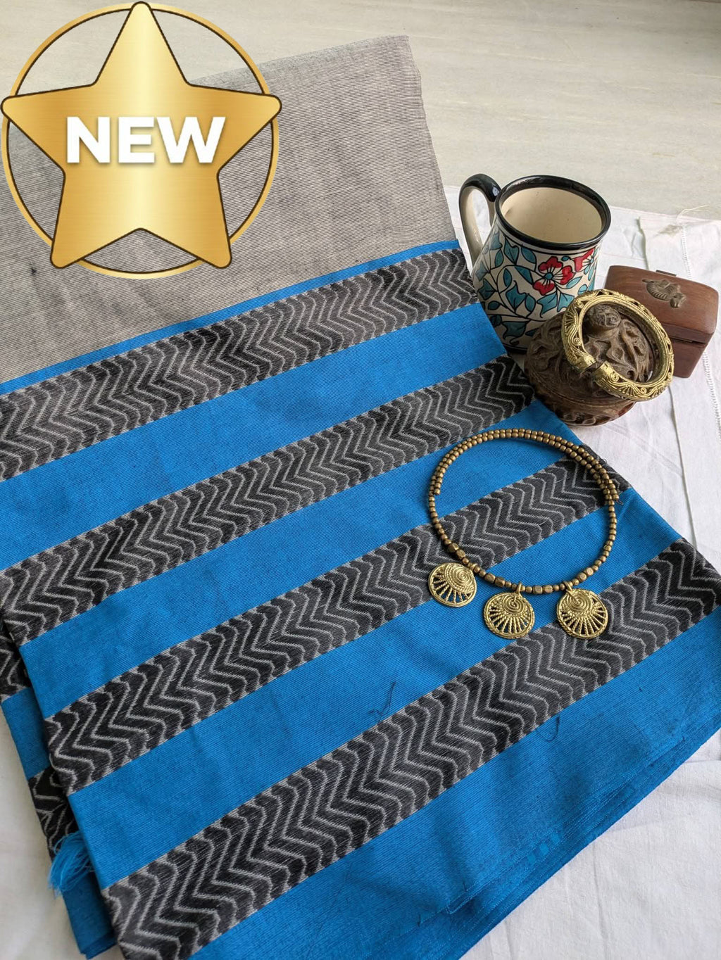 Blue and gray striped fabric with a mug, small bowl, and jewelry on a light wooden surface.