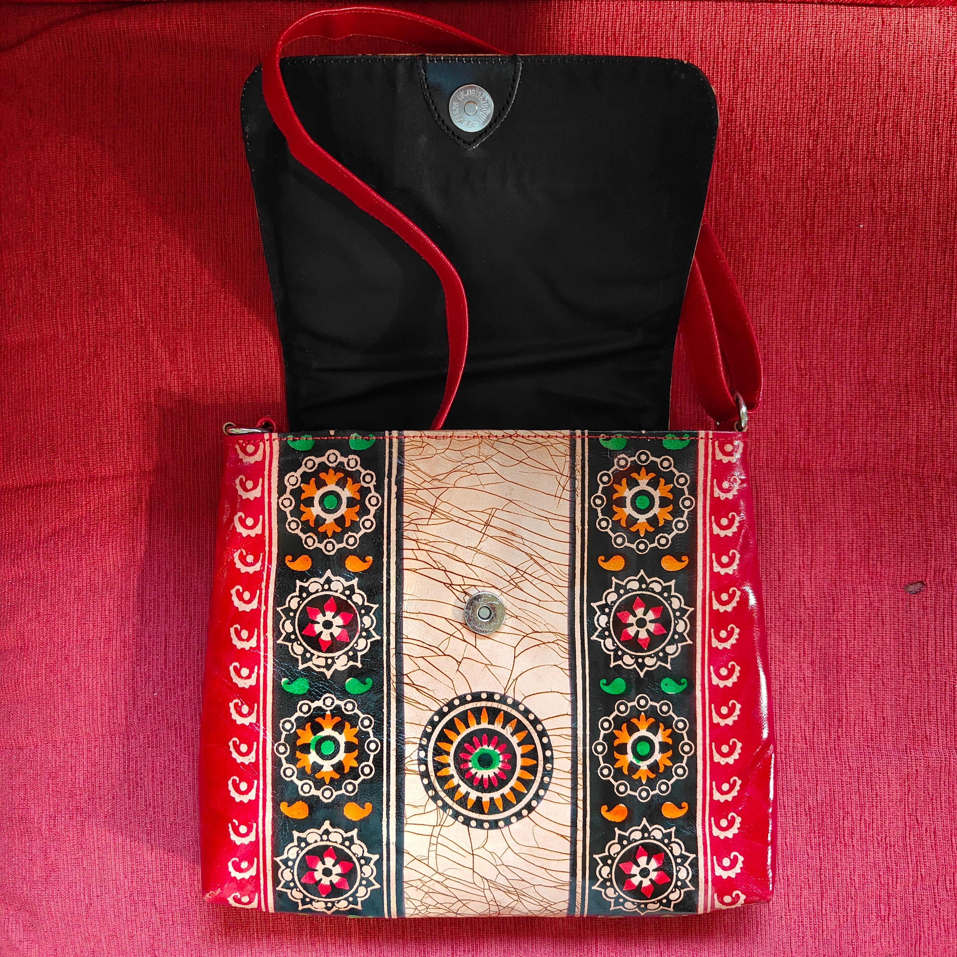 Black bag with red strap and decorative pattern on a red background