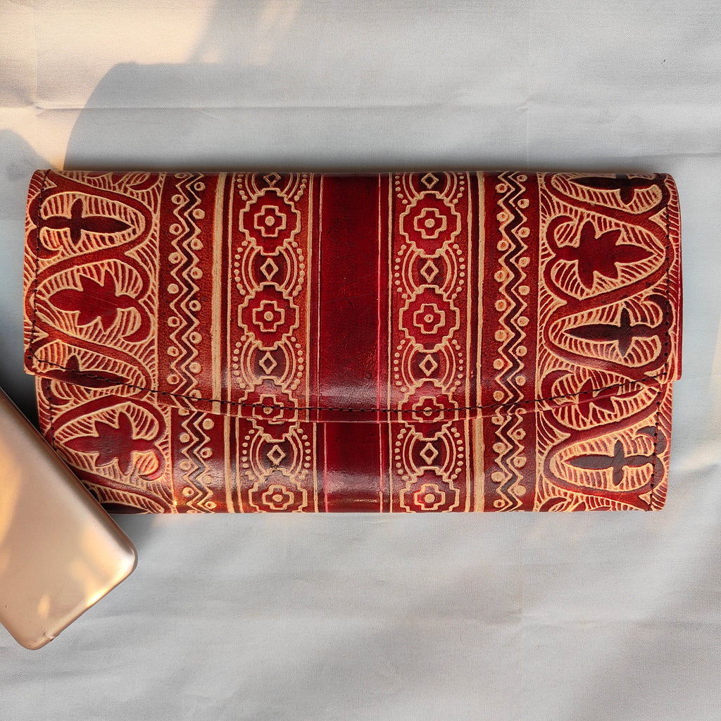 Roll of red fabric with intricate patterns on a white background