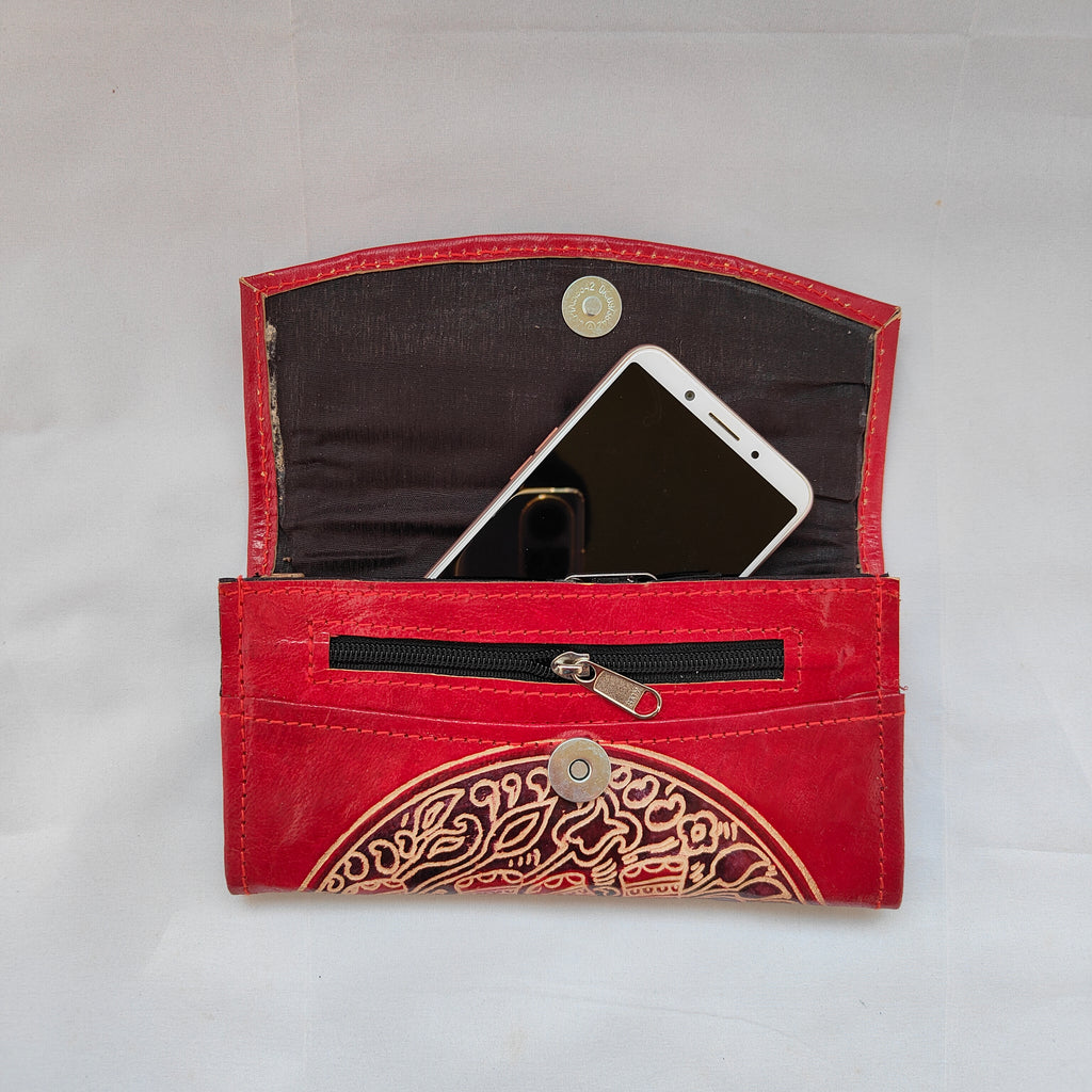 Red wallet with intricate design holding a smartphone on a light gray background