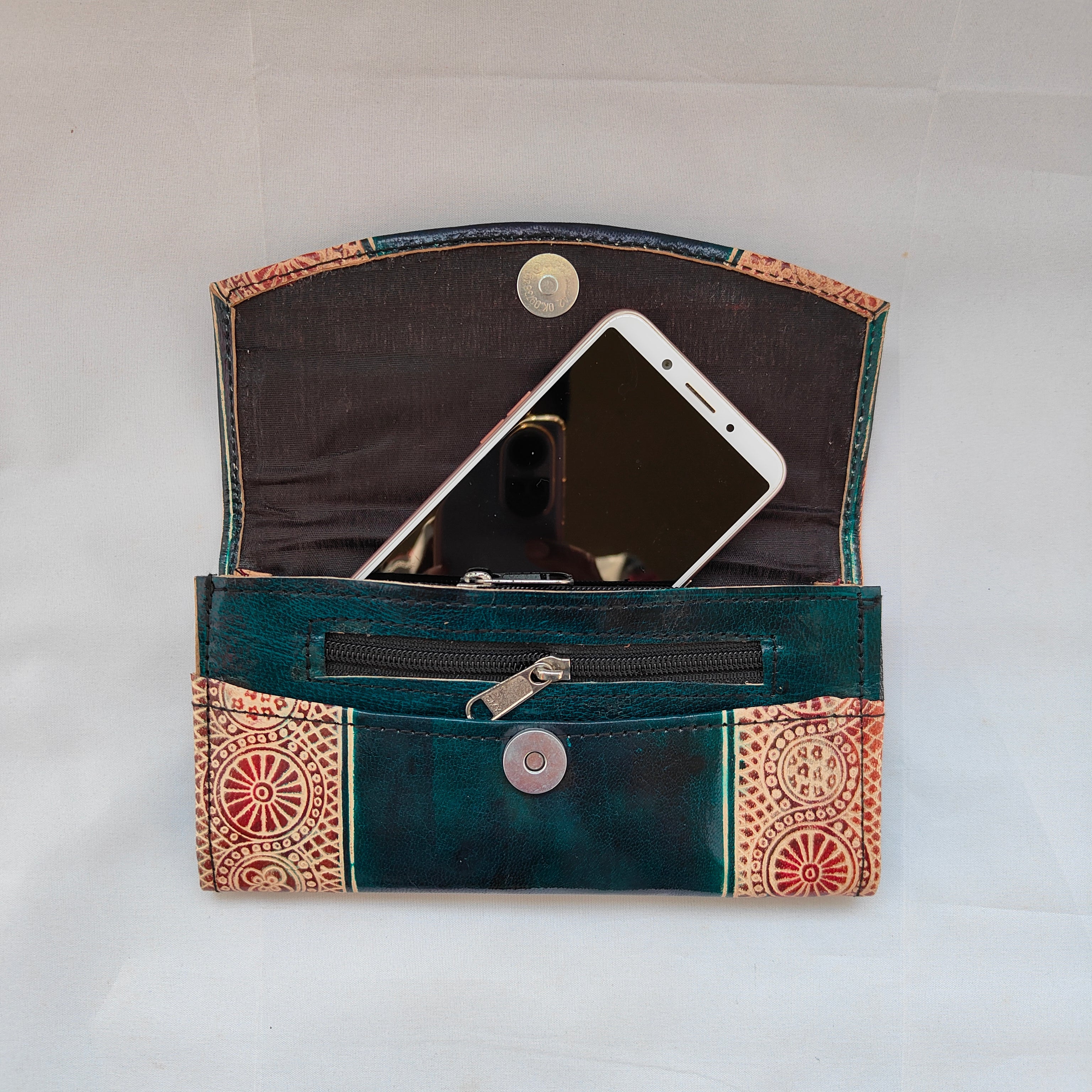 Green wallet with decorative patterns containing a smartphone on a white background