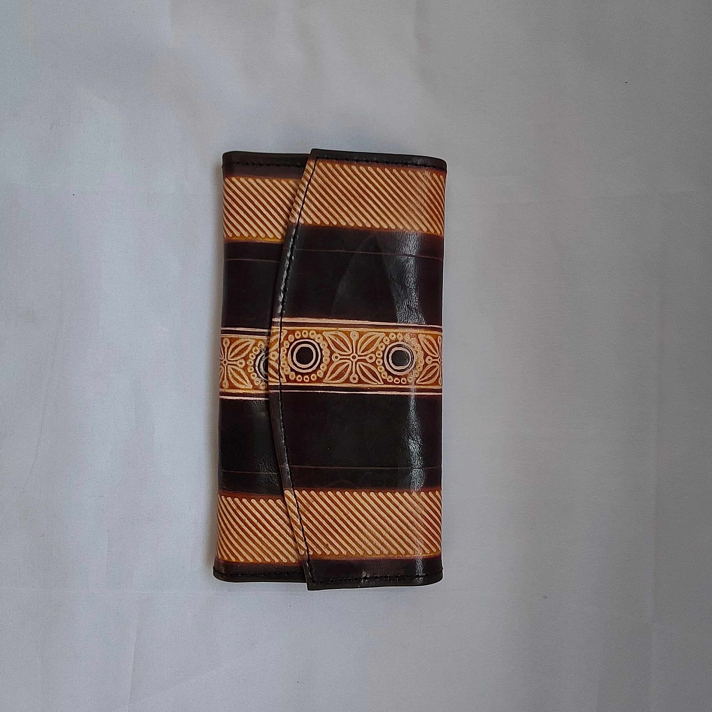 Black and brown striped wallet with decorative band on a white background