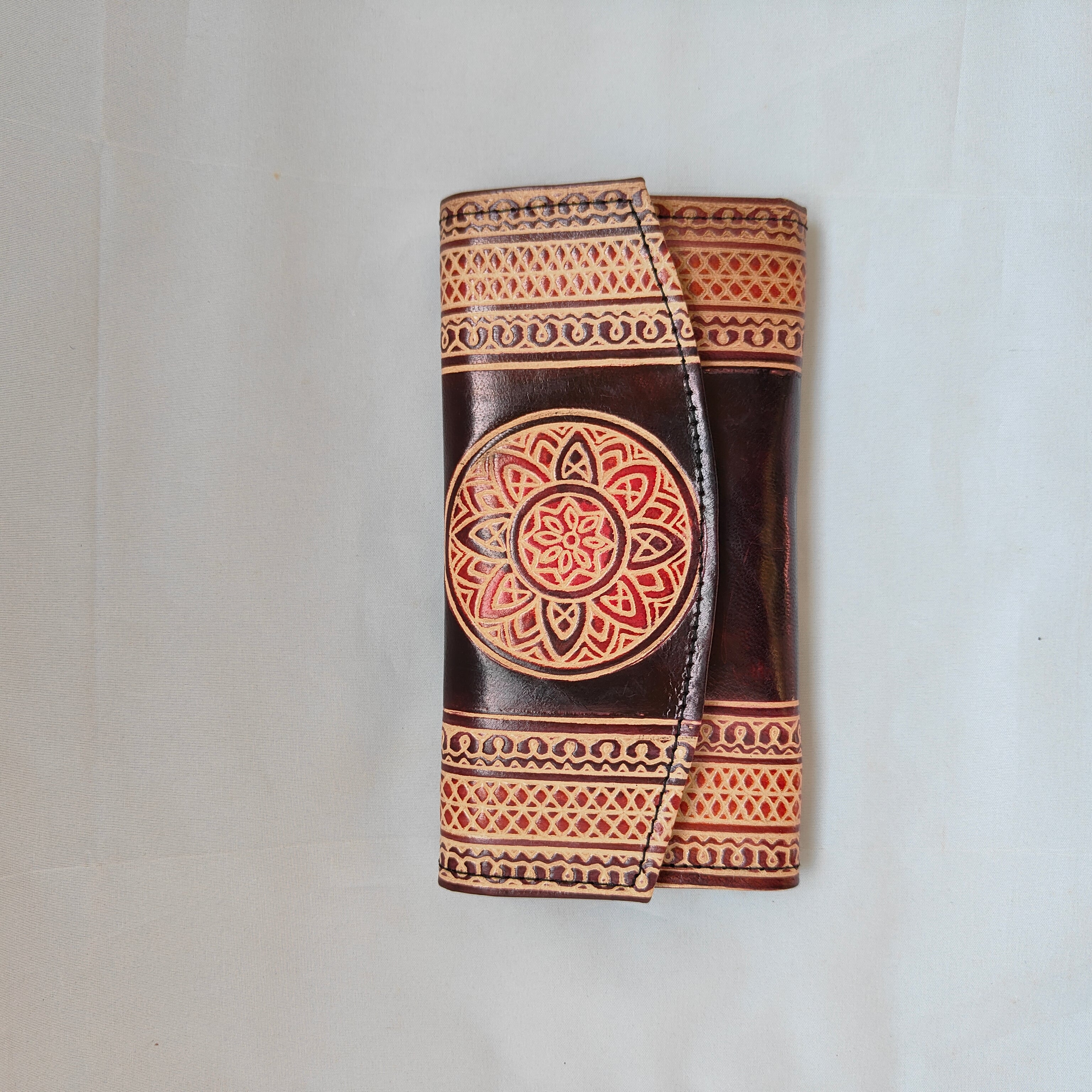 Decorative leather wallet with intricate patterns on a white background