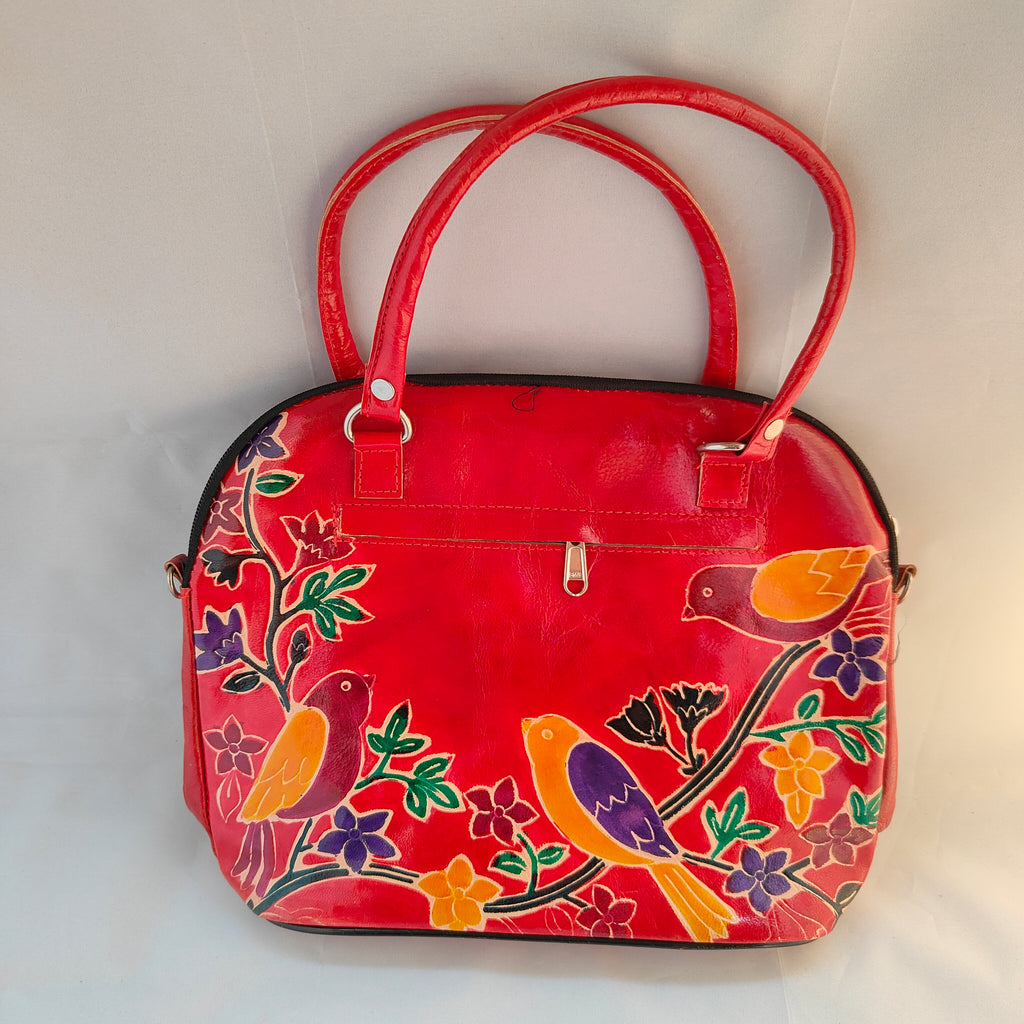 Red handbag with colorful bird and floral patterns on a white background