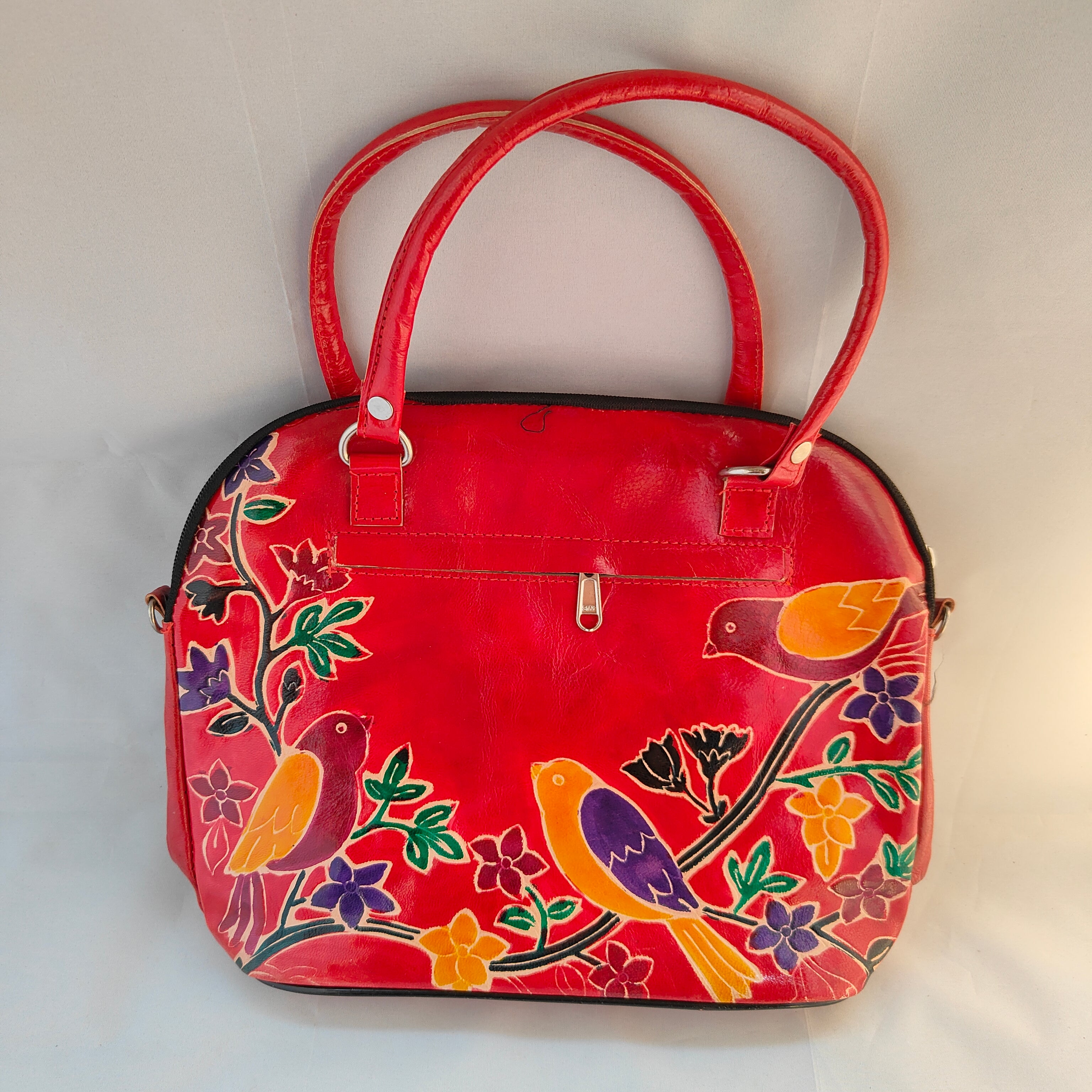 Red handbag with colorful bird and floral patterns on a white background