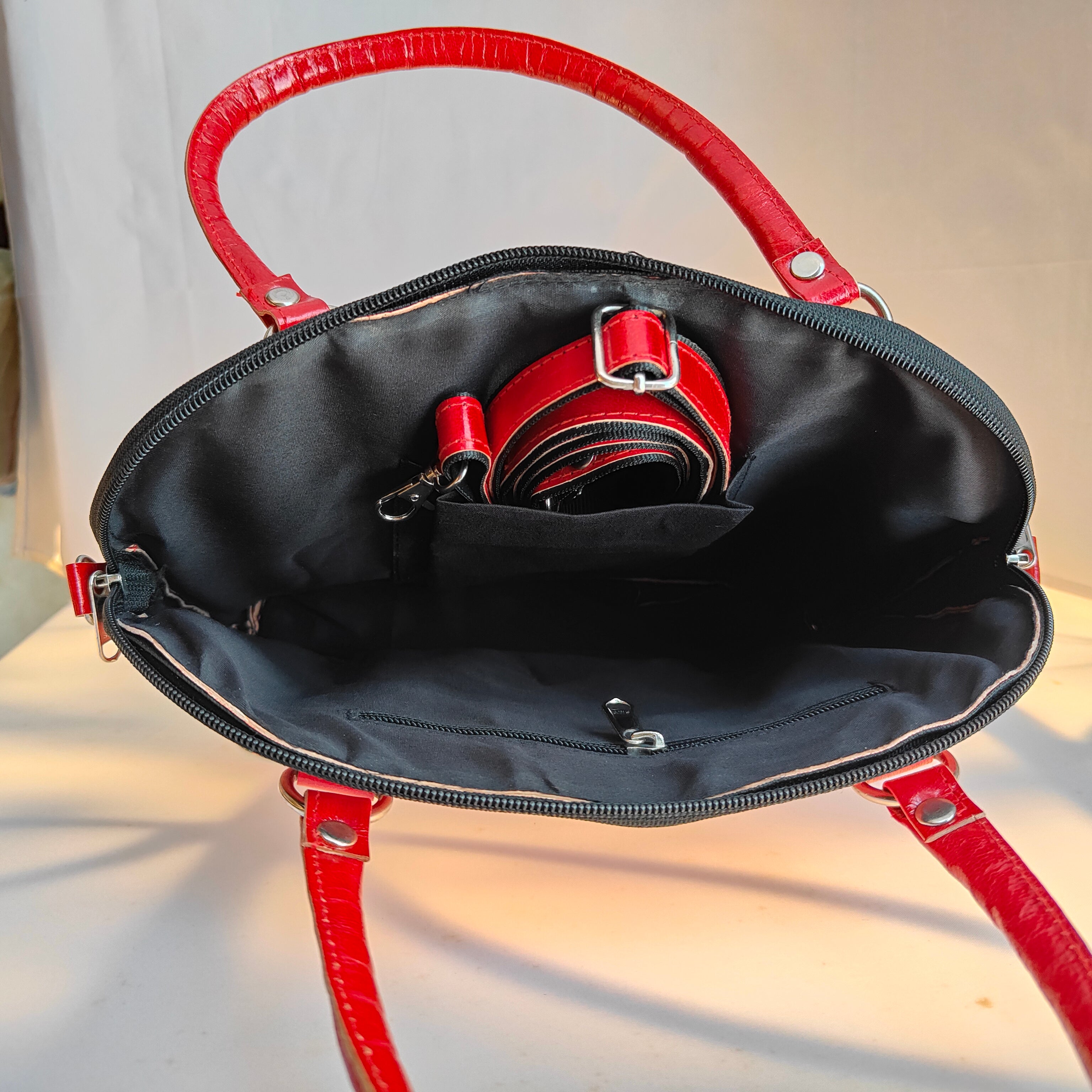 Red handbag with open top showing black interior on a white background
