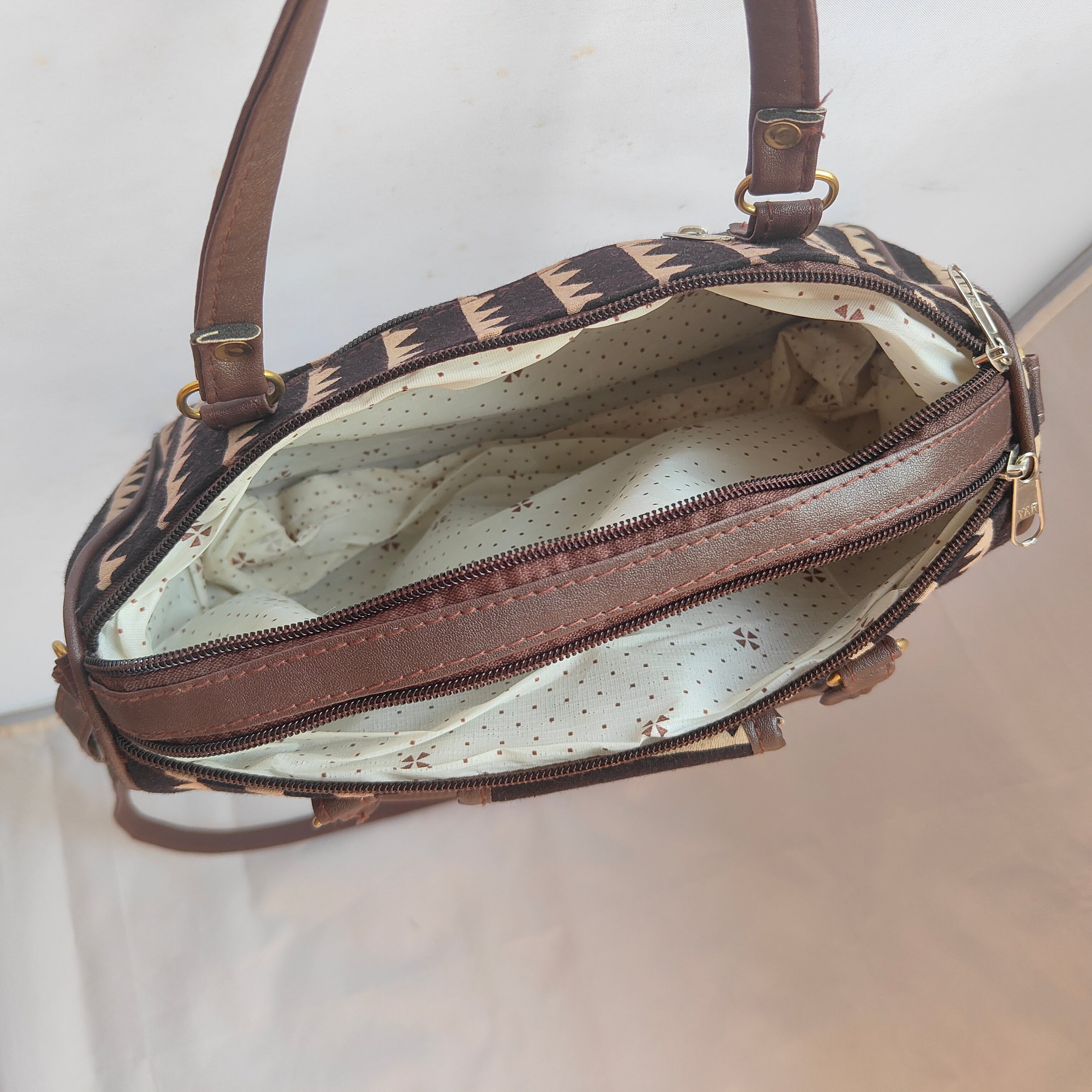 Brown handbag with patterned interior on a light background