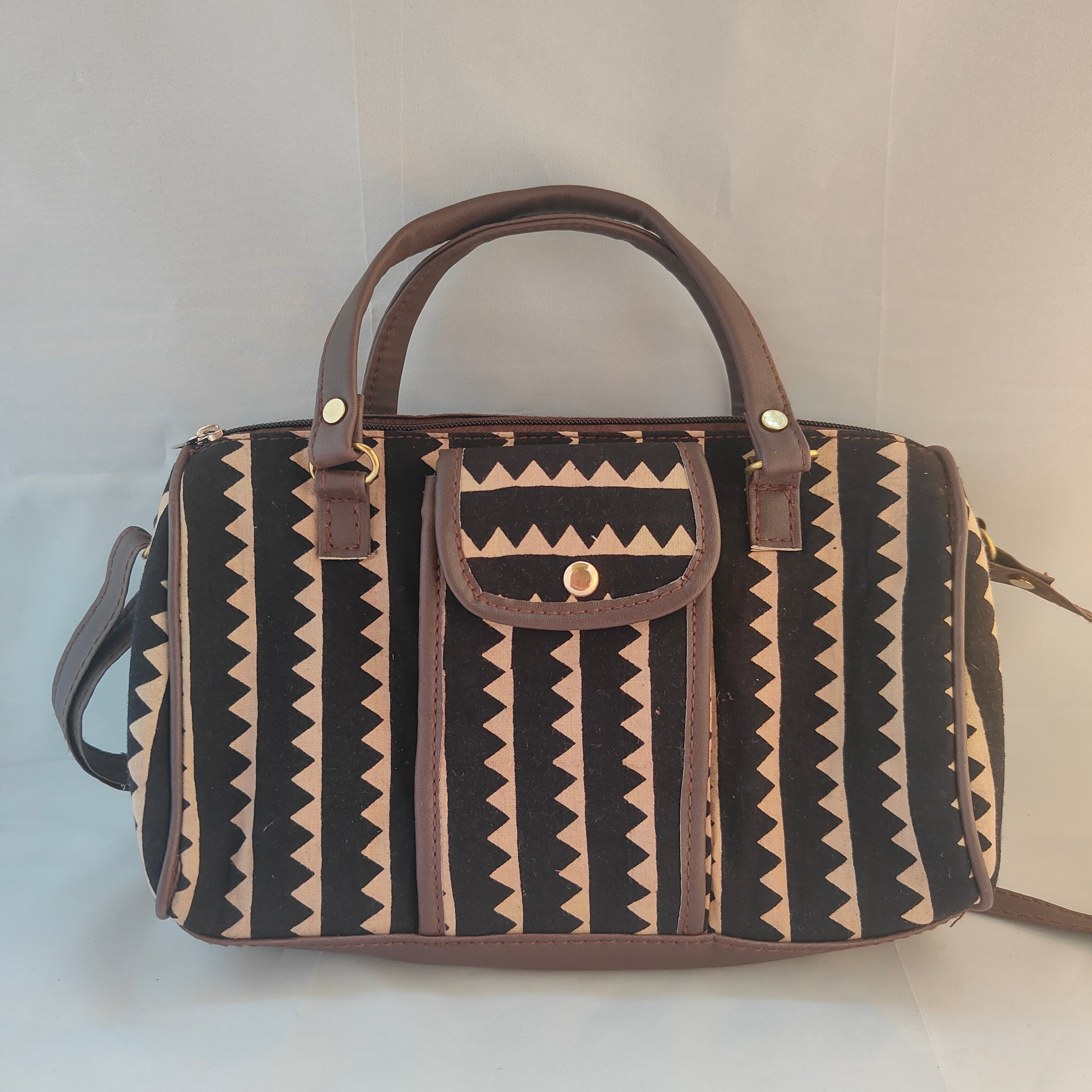 Patterned handbag with brown handles and trim on a light background