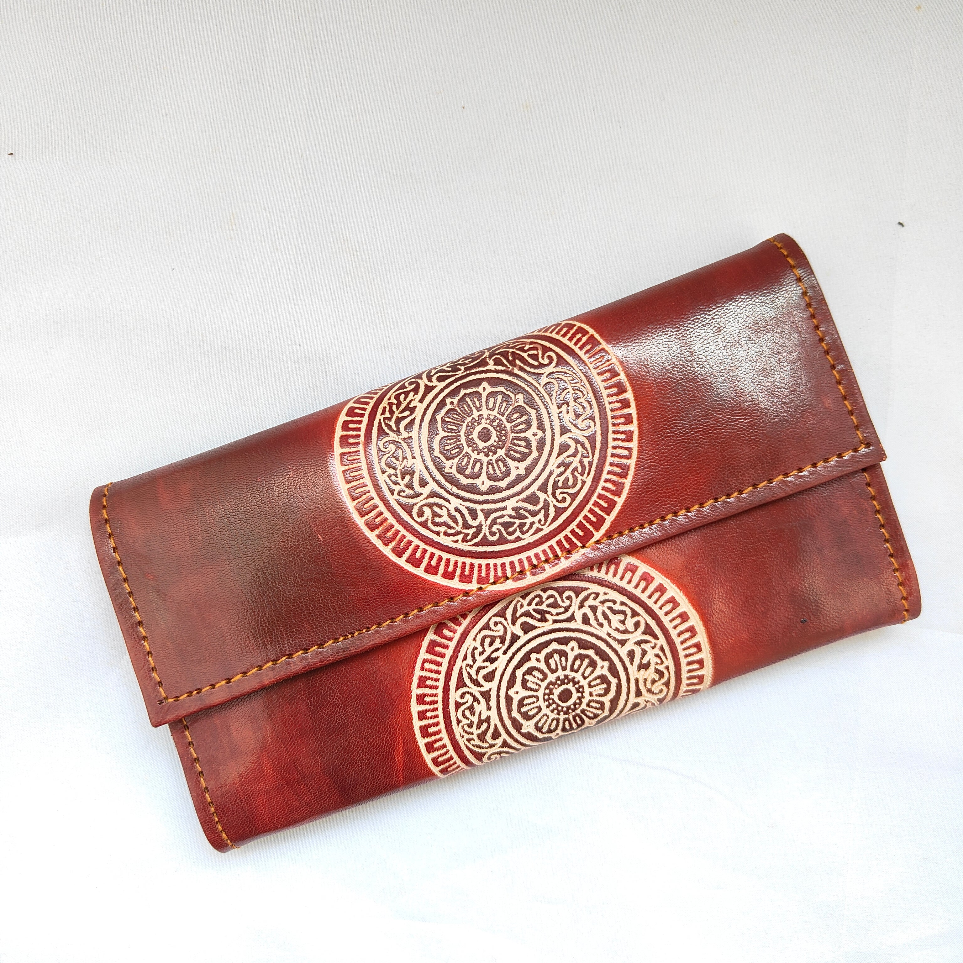 Brown leather wallet with intricate white patterns on a white background