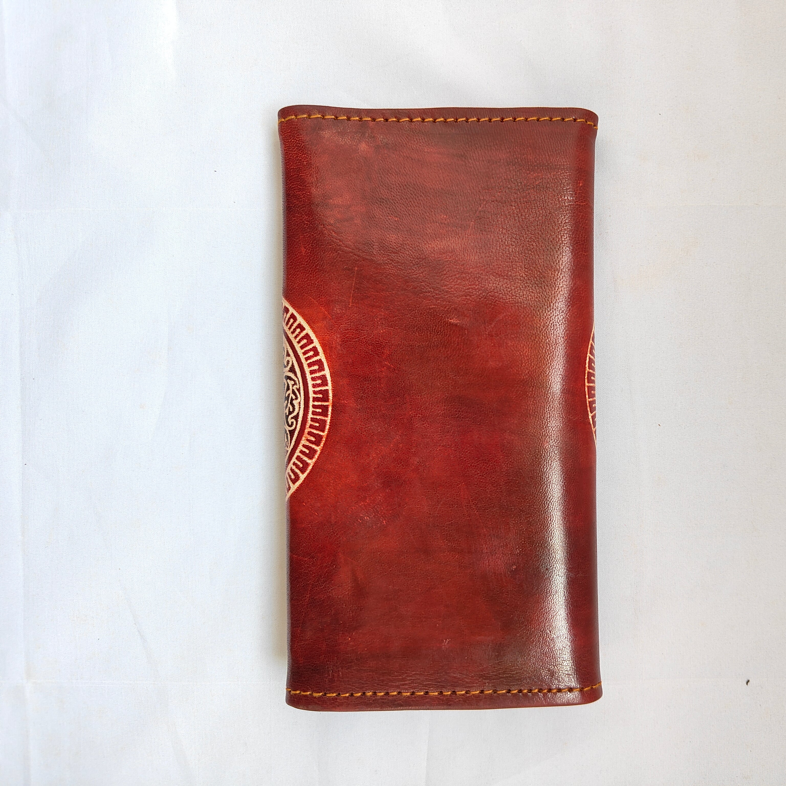 Brown leather wallet with a circular emblem on a white background
