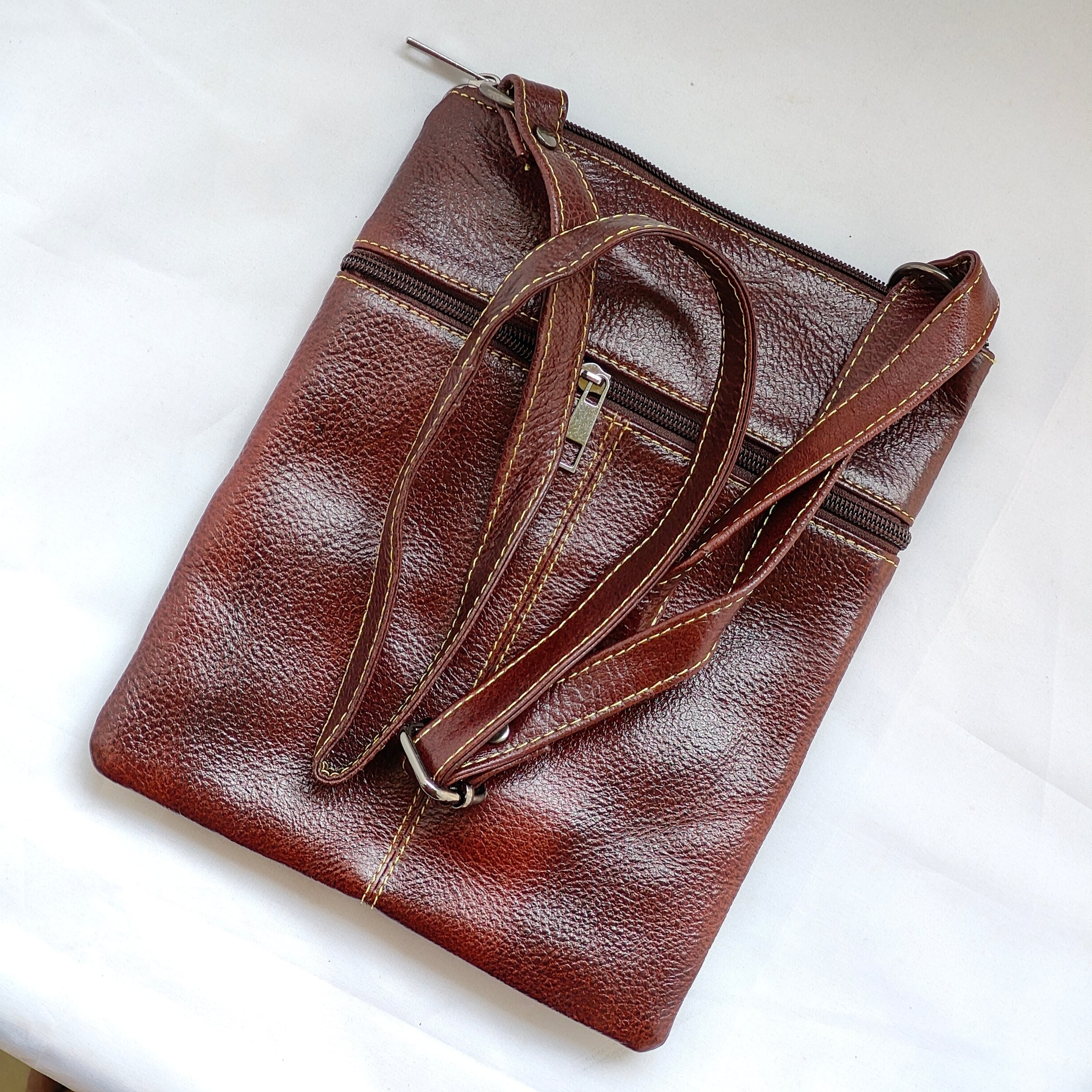 Brown leather clutch bag with a strap on a white background