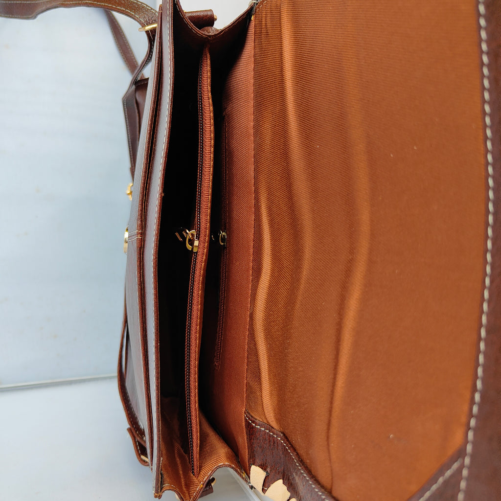 Close-up of a brown leather bag with visible stitching on a white background
