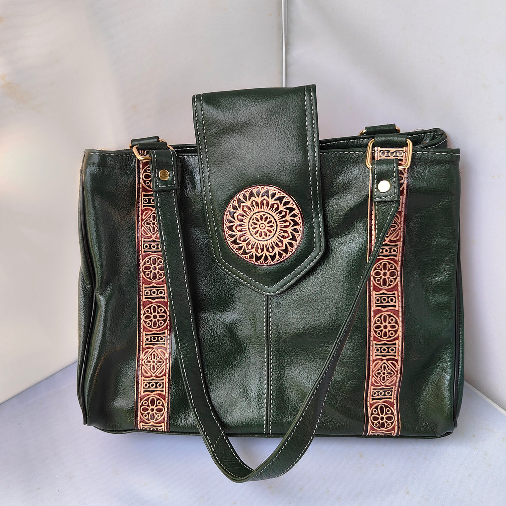 Green leather handbag with decorative straps on a light gray background