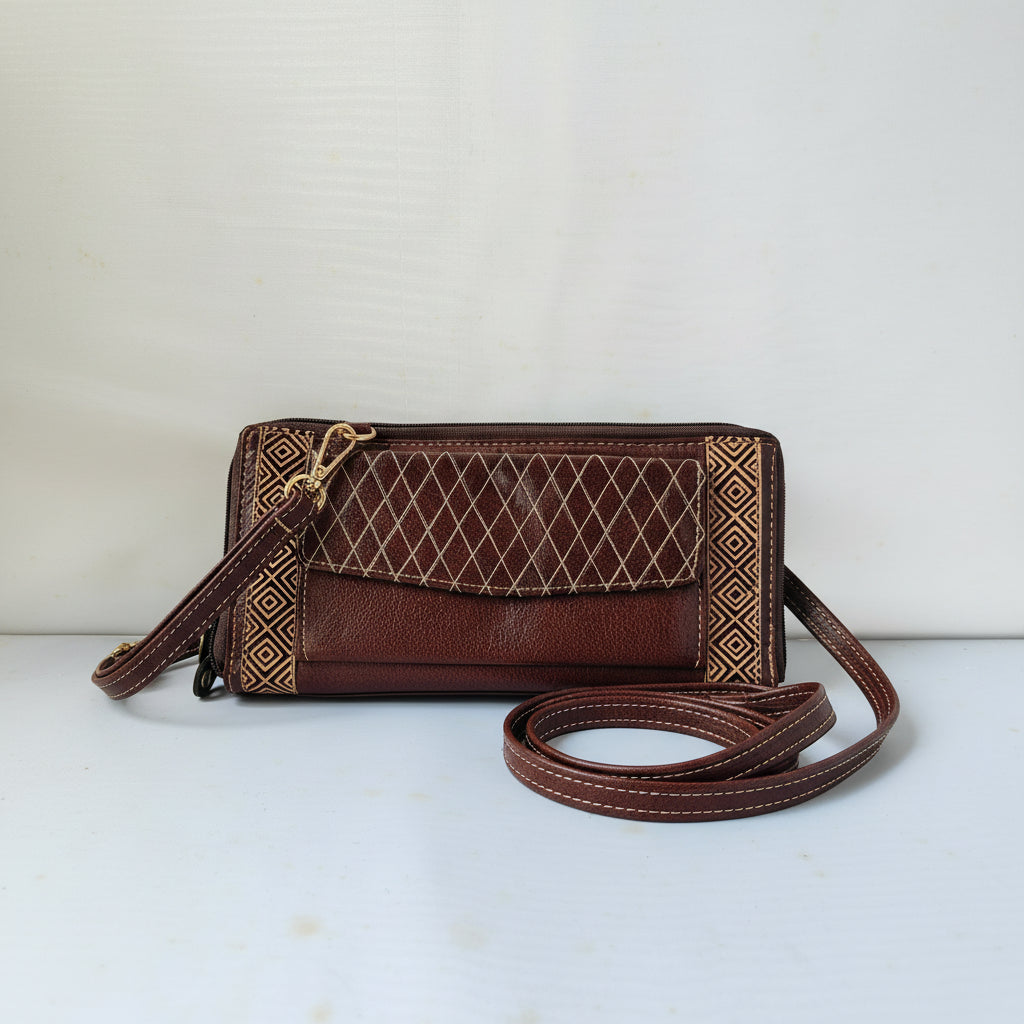 A brown leather crossbody clutch bag with gold geometric patterns on the borders and a quilted diamond design on the front flap, featuring a matching adjustable shoulder strap.
