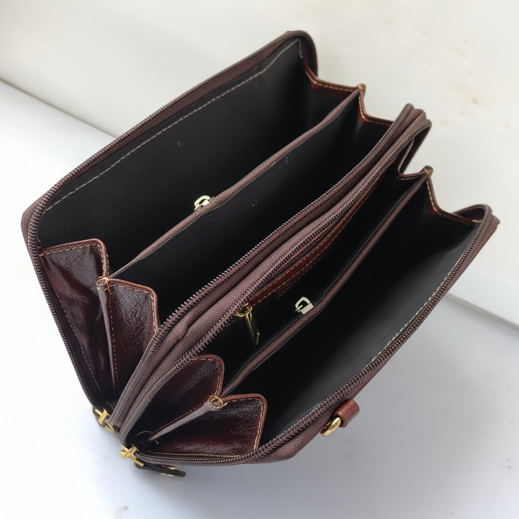 A dark brown leather multi-compartment wallet shown open, displaying its interior card slots, zippered compartments, and gold-tone zipper pulls on a light-colored surface.