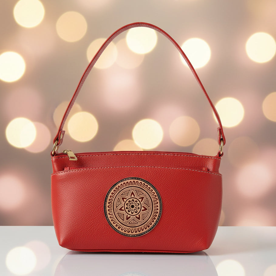 A red leather shoulder bag with a zippered top and a prominent circular gold-toned medallion on the front, set against a plain off-white background.