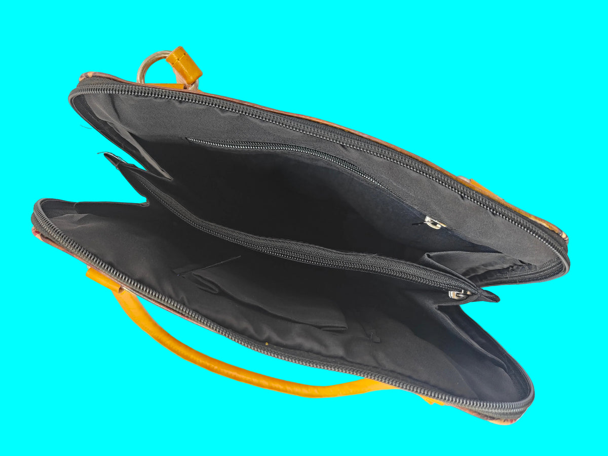 An open black zippered laptop sleeve or carrying case with a bright orange handle and trim, photographed from above on a light gray surface.