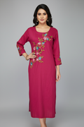 A woman modeling a magenta pink straight-cut kurta with floral embroidery on the chest and cuffs, set against a solid gray studio background.
