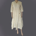 Mannequin wearing a beige embroidered dress against a dark background