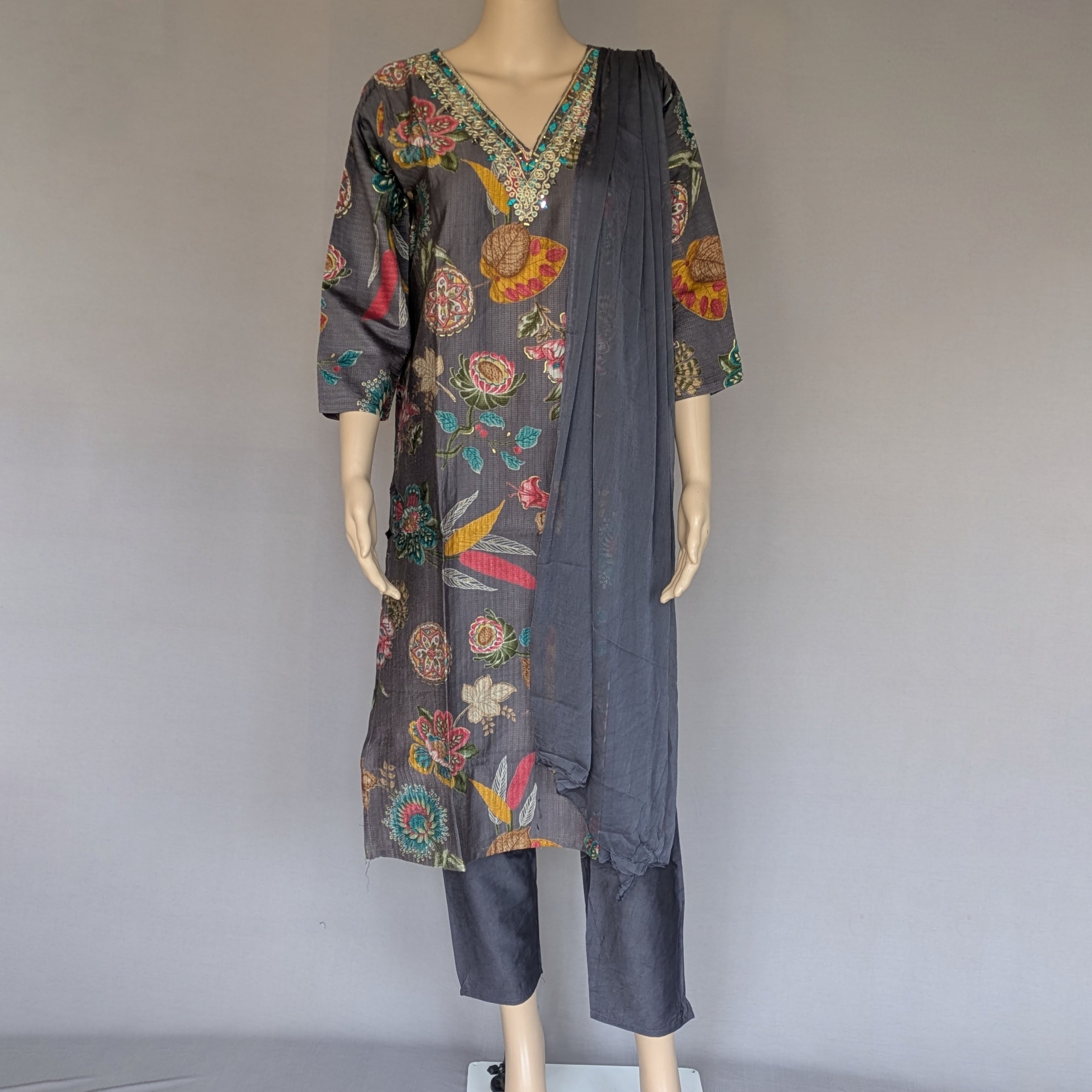 Mannequin wearing a dark gray outfit with colorful floral patterns on a plain background