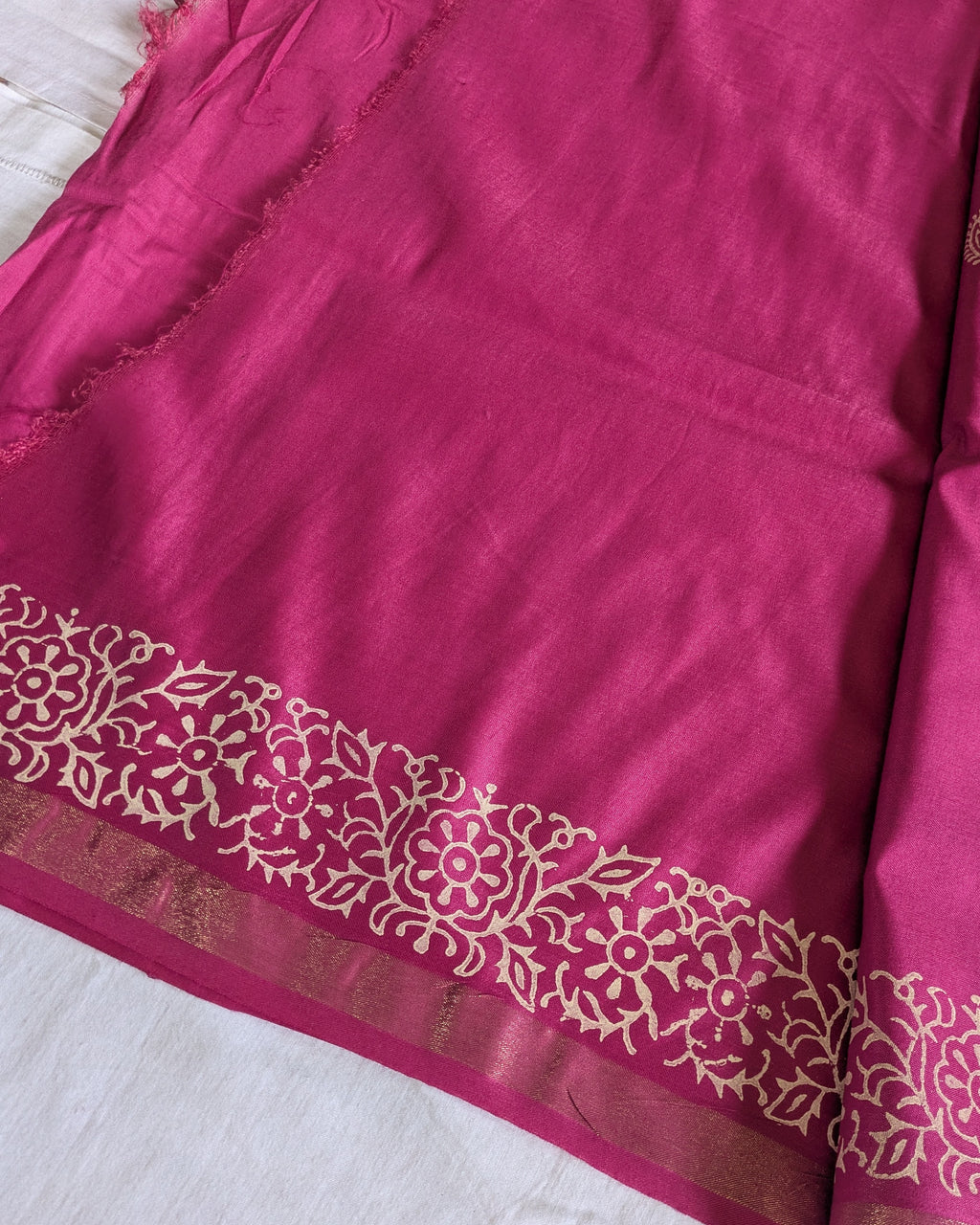 Close-up of a pink fabric with intricate white patterns on a white background