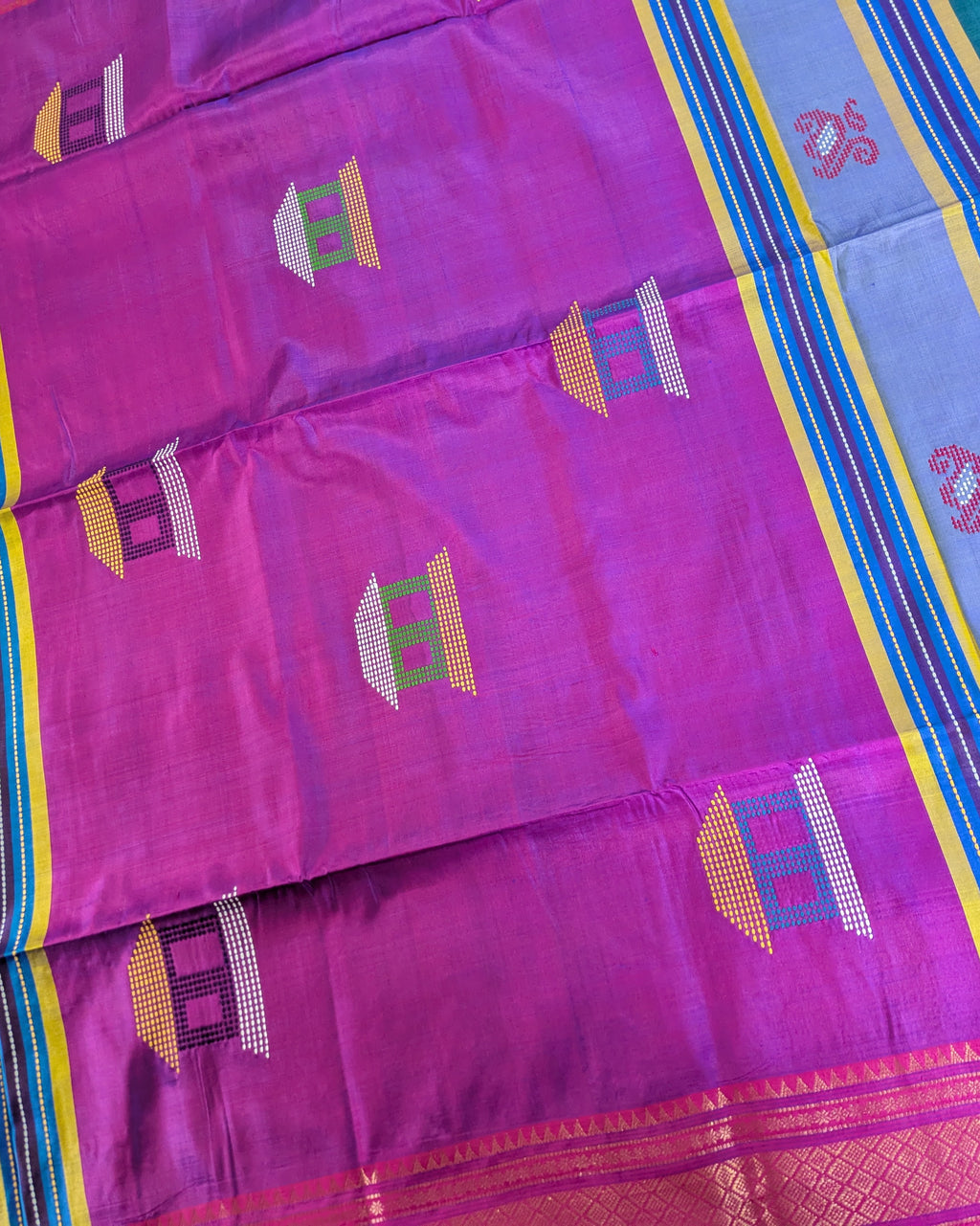 A close-up of a purple silk saree with geometric motifs in green, yellow, and white, and a blue border with yellow and blue stripes.
