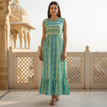 Woman wearing a green and blue striped dress standing on a balcony with architectural background
