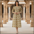 Woman in a floral dress standing in an architectural setting with columns.