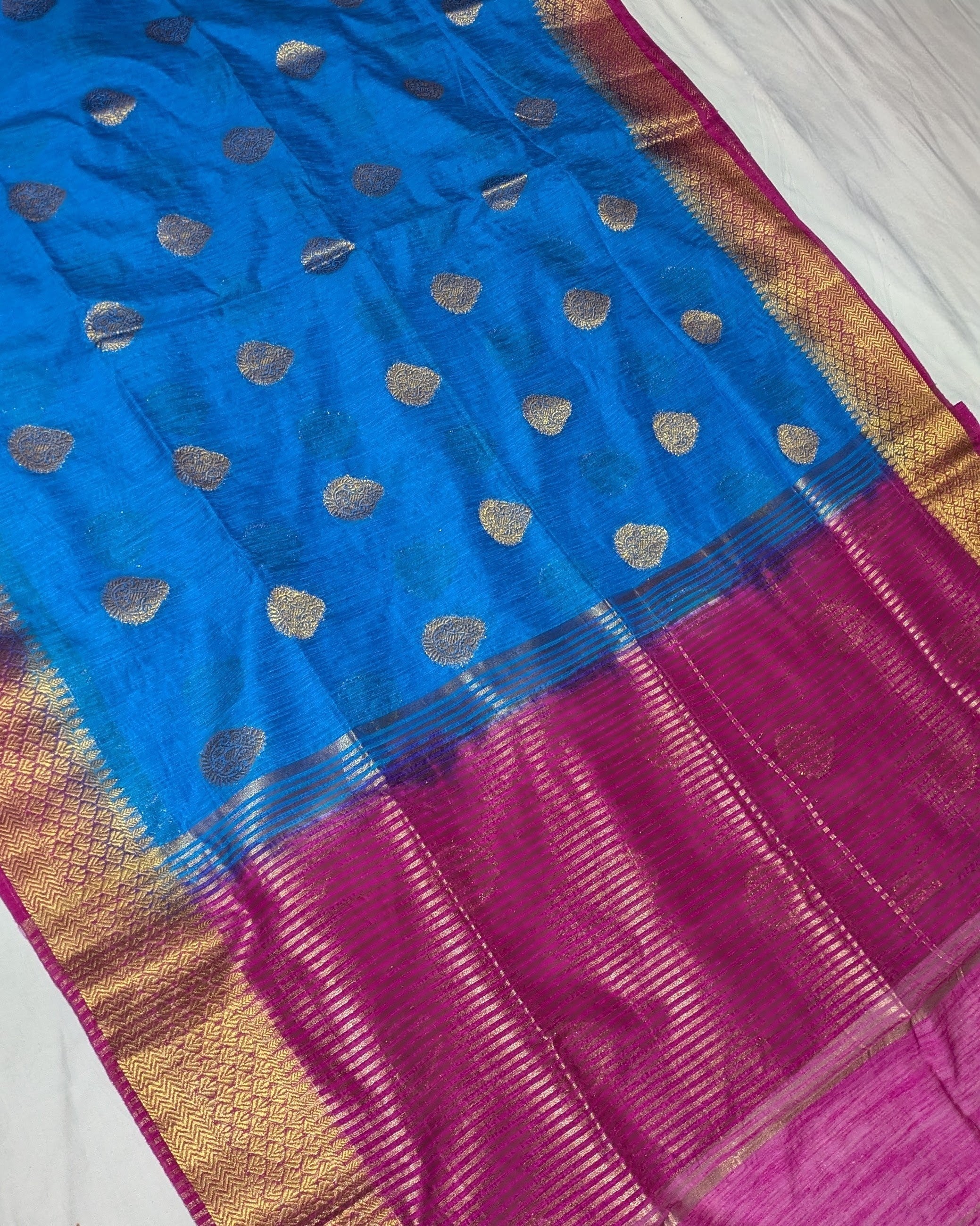 Blue and pink saree with gold border on a white background