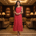 Woman in a red dress standing in an elegant indoor setting with beige sofas and decorative lamps.